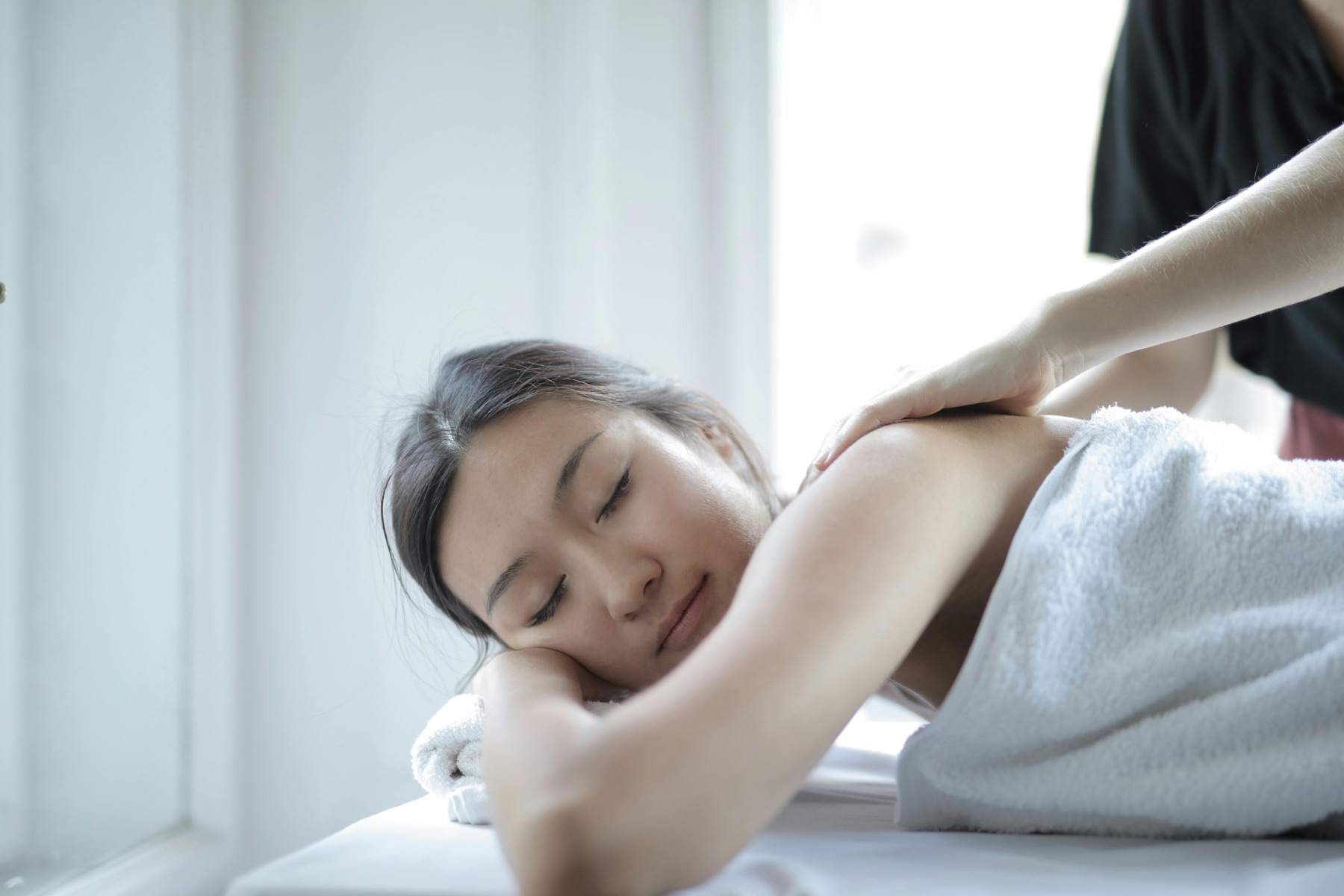 Guest receiving a relaxing shoulder massage in a bright spa treatment room
