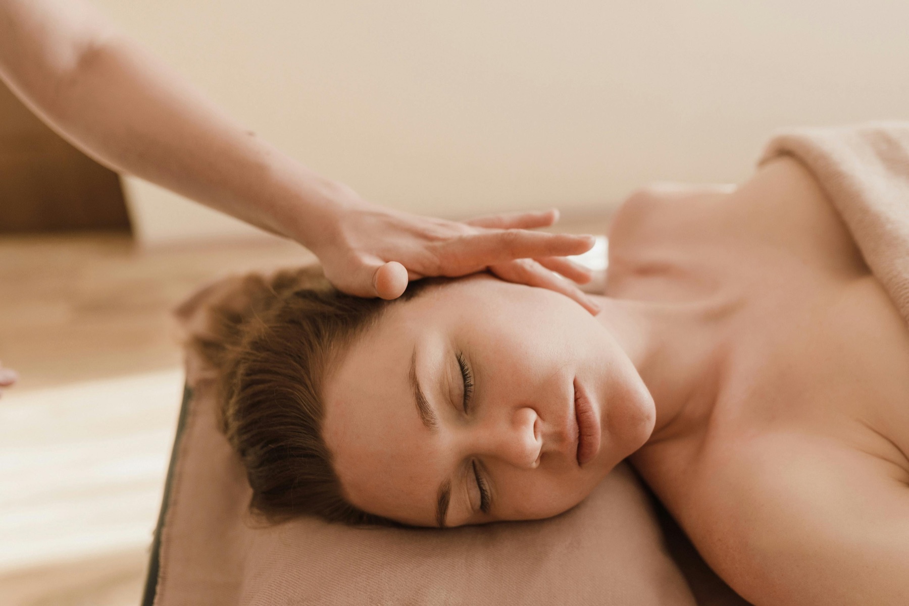 Client resting during a calming head massage in a warm spa setting